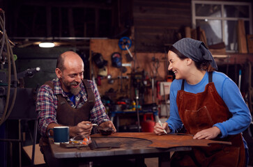 Male And Female Blacksmith Working On Design In Forge Together