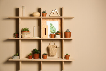 Fototapeta na wymiar Wooden shelves with different decorative elements on beige wall, space for text