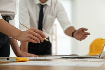 People working with construction drawings at table, closeup