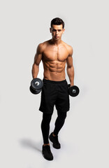Full length image of a confident young man shirtless torso portrait training with dumb-bell, isolated white background.