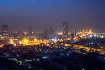 Fototapeta premium The high angle background of the city view with the secret light of the evening, blurring of night lights, showing the distribution of condominiums, dense homes in the capital community