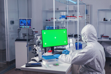 Fototapeta na wymiar Medical engineer conducting research on computer with green screen during covornavirus. Team of microbiologists doing vaccine research writing on device with chroma key, isolated, mockup display.