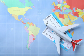 Fototapeta na wymiar Toy airplane and tickets on world map, flat lay. Travel agency concept