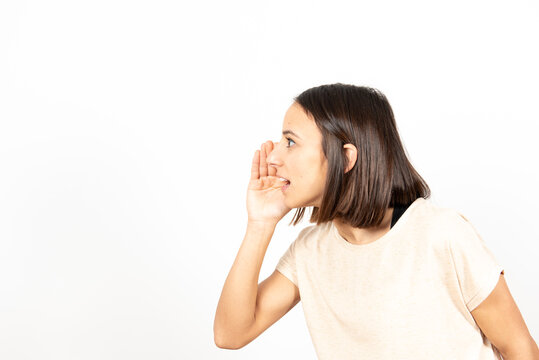 Side View Of A Latin Woman Telling A Secret In The Direction Of Copy Space.