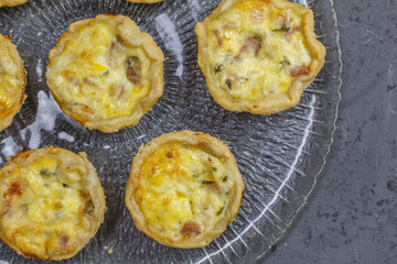 Mini quiche photo - many small savory tartlets on glass serving plate - top view image