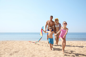 Happy family with kite at beach on sunny day