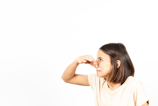 Bad smell concept. Side view of a young latin woman pinching her nose with nasty face.