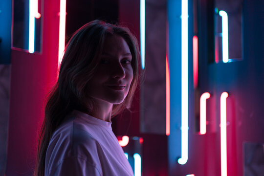 Woman's smile in the light of neon. Glamorous beauty looks into the camera