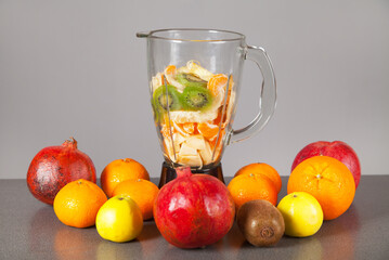 Blender and fruits on an isolated gray background.