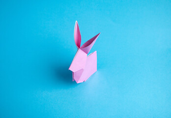 Step-by-step instructions for creating  origami bunny out of colored paper on  blue background, for...