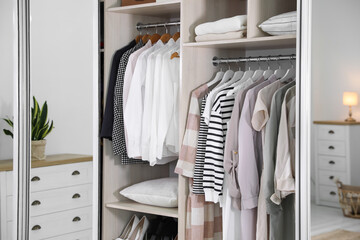 Wardrobe closet with different stylish clothes in room, closeup