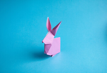 Step-by-step instructions for creating  origami bunny out of colored paper on  blue background, for  decorative Easter party decoration or for small Easter gifts. - obrazy, fototapety, plakaty