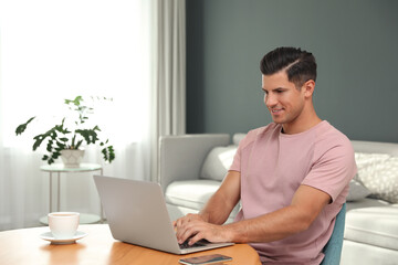 Man using laptop for search at wooden table in living room