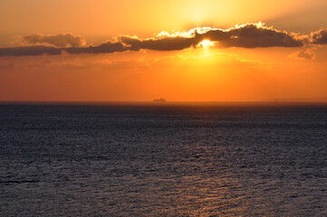 Beautiful sunset ,a ship at horizon ,sun shines over clouds. Selective focus.