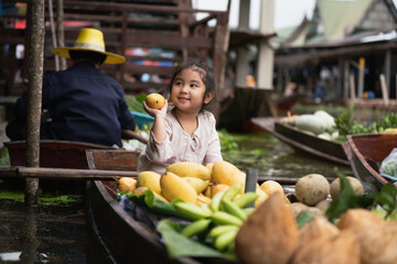 little girl in floating market,  suppermarket on boat local market in thailand, little girl have smiling on floating market.