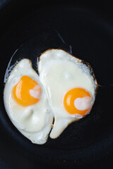fried eggs in a black frying pan, close-up.