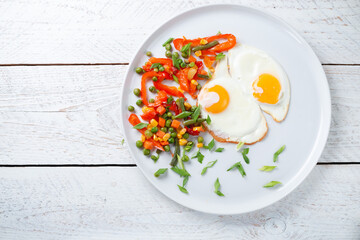 Fried eggs and vegetables in a white plate.