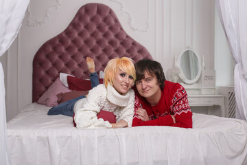 Cheerful romantic couple on bed at home laughing, enjoying free time together joking
