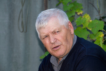 Old gray-haired man is not looking at camera.