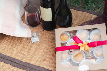 Outdoors area decorated for the party in a garden with a wine bottle, a glass, dessert in a box. Concept of relaxation