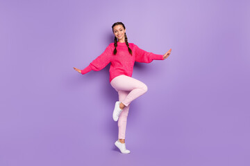 Fototapeta na wymiar Full length photo of stunning happy charming woman raise palms wear pink sweater trousers isolated on purple color background