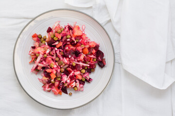 Russian traditional salad with vegetables - vinaigrette on a plate  on a table on a cloth. Top view. Copy space