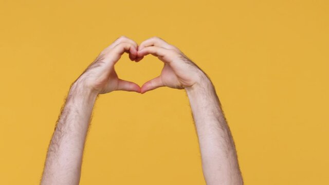 Cropped close up man male showing shape heart with hands heart-shape sign love Valentines day gesture isolated on yellow background studio. Copy space commercial promo. Advertising workspace mock up
