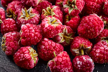 Close up heap of fresh raspberries on dark background