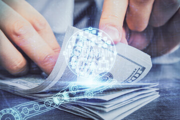 Multi exposure of blockchain theme drawing hologram and USA dollars bills and man hands. Business concept.