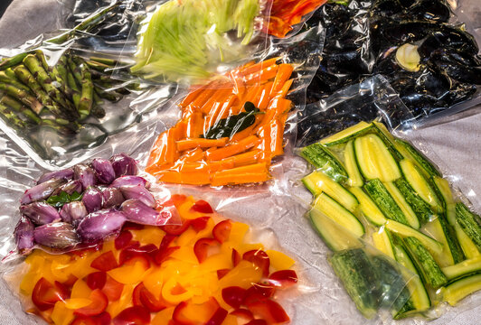 vacuum sealed bags for sous vide cooking with peppers and courgettes and shallots, fresh carrots and asparagus and mussels