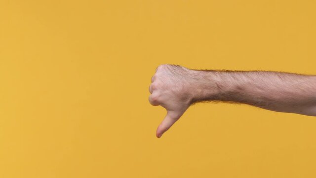 Cropped close up man horizontal male hand showing different signs thumbs up down like dislike gesture isolated on yellow background studio. Copy space commercial promo advertisement workspace mock up
