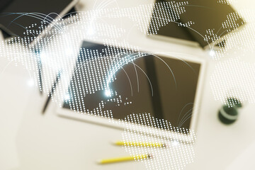 Double exposure of abstract digital world map with connections and digital tablet on background, top view, research and strategy concept