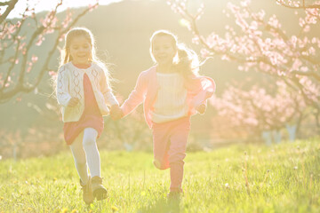 Fototapeta na wymiar Children outdoors in sunlight. Children run holding hands in the park. High quality photo.