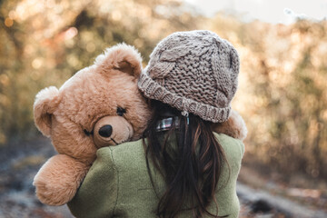 Little girl hugs her bear on a background of nature, autumn, durba. - 408527333