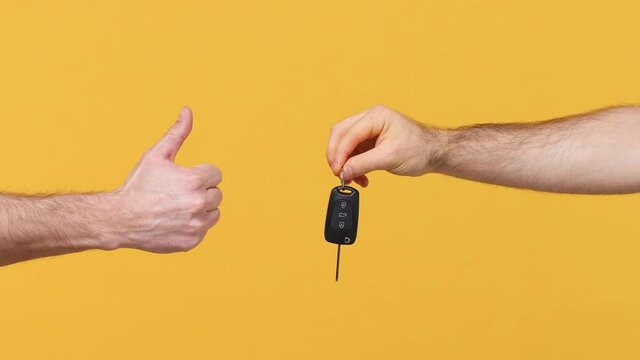 Close up cropped man male hand hold gift car key thumb up like gesture isolated on yellow background studio. Birthday holiday concept. Copy space commercial advertisement Advertising workspace mock up