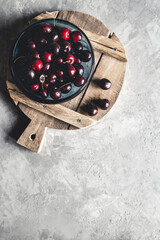 top view of red cherries on a bowl with slices of peaches on a wooden kitchen board