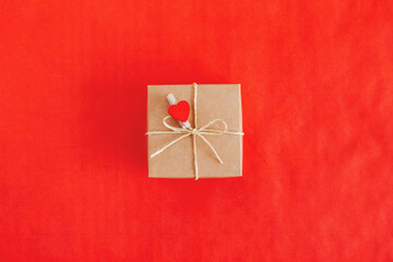 Craft gift box with red heart on a red background. Holiday concept for Valentine's day.