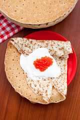 Pancake with red caviar and sour cream during Shrovetide