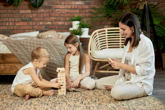 Mom and kids play squirl tower. Woman girl and boy play family puzzle game. Family day off