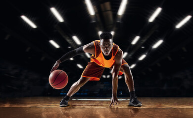 Ready to jump. African-american young basketball player in action and motion in flashlights over...