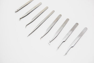 tools for eyelash extension and eyebrow design. cosmetic tweezers in silver color on a white background