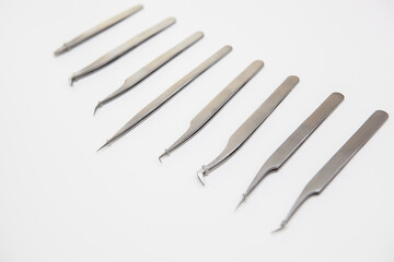 tools for eyelash extension and eyebrow design. cosmetic tweezers in silver color on a white background