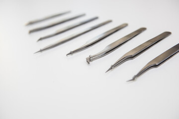 tools for eyelash extension and eyebrow design. cosmetic tweezers in silver color on a white background