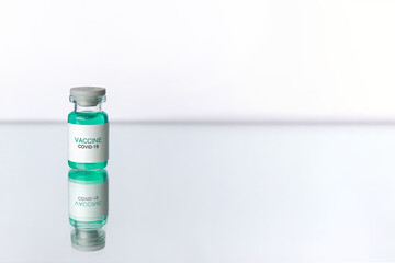 Development and creation of a coronavirus vaccine COVID-19. Ampoule on white reflective surface. Healthcare and medical concept.
