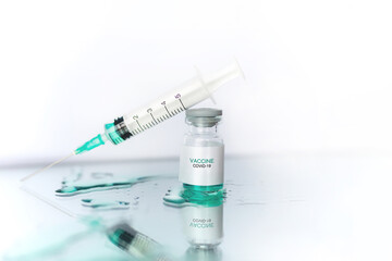 Development and creation of a coronavirus vaccine COVID-19. Ampoule and syringe. Spilled liquid on white reflective surface. Healthcare and medical concept.