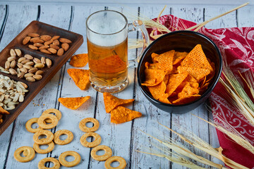 Assorted snacks, chips, and a glass of beer on blue table