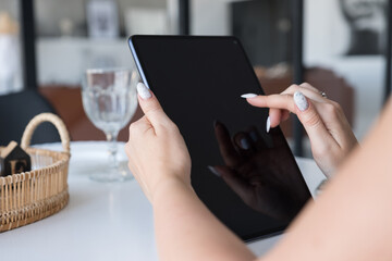 Brunette Caucasian woman in white blouse and black skirt working via internet using tablet. Work from home concept. Space for text