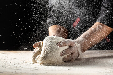 Photo of flour and men hands with flour splash. Cooking bread. Kneading the Dough. Isolated on dark background. Empty space for text