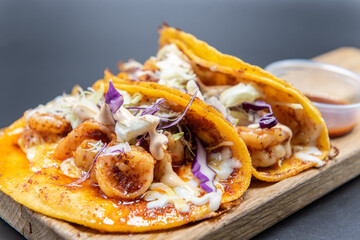 Mexican tacos encabronados served with shrimp on a wooden cutting board.
