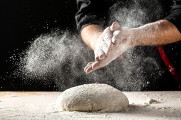 Photo of flour and men hands with flour splash. Cooking bread. Kneading the Dough. Isolated on dark...